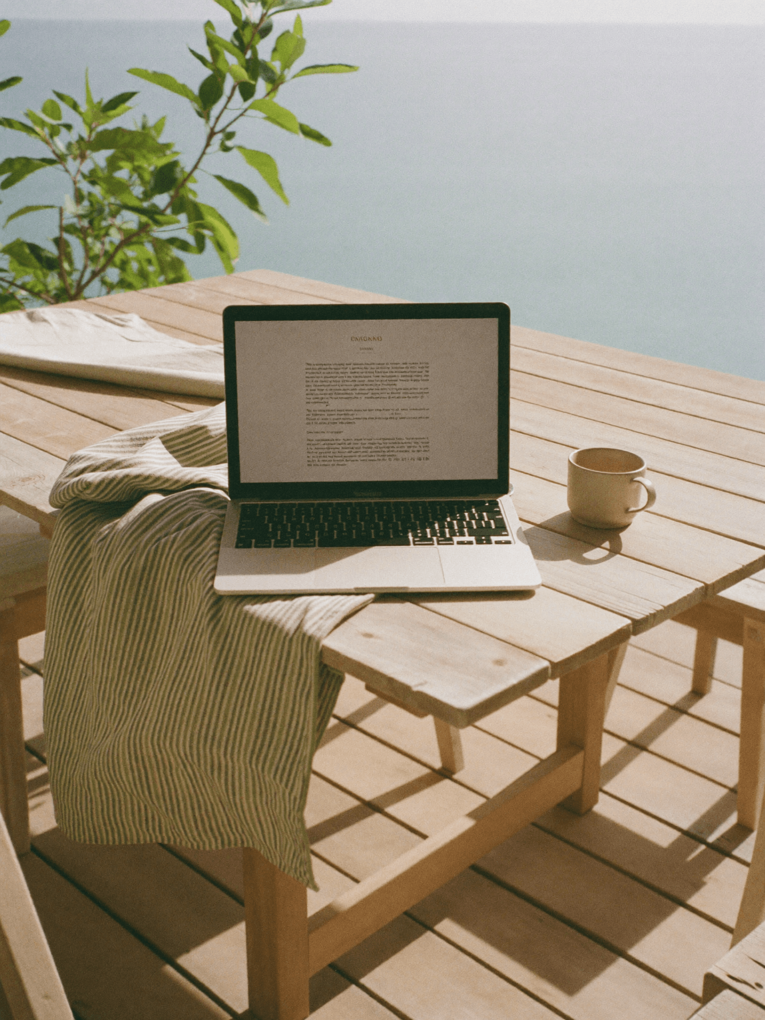 Laptop and coffee on a sunlit deck